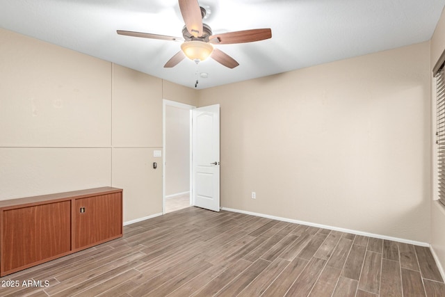 spare room with baseboards, ceiling fan, and wood tiled floor