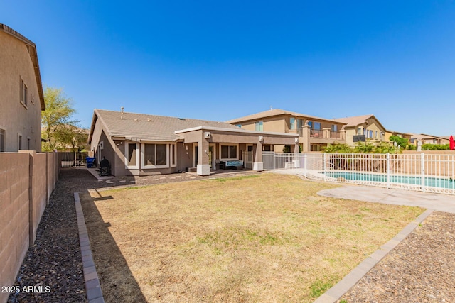 rear view of property with a fenced in pool, stucco siding, a lawn, a fenced backyard, and a patio area