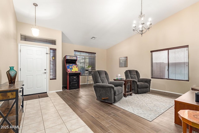 living area featuring visible vents, baseboards, a chandelier, lofted ceiling, and wood finished floors