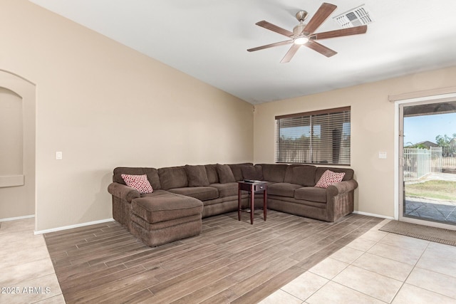 living area with visible vents, ceiling fan, baseboards, light wood-type flooring, and lofted ceiling