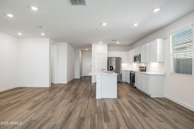 kitchen featuring stainless steel appliances, wood finished floors, a sink, visible vents, and open floor plan