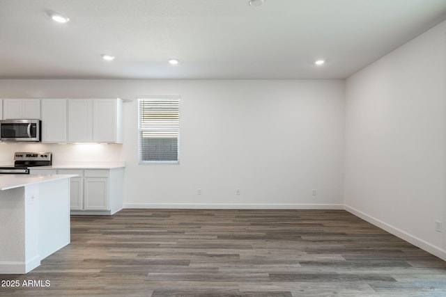 kitchen with appliances with stainless steel finishes, wood finished floors, light countertops, white cabinetry, and recessed lighting