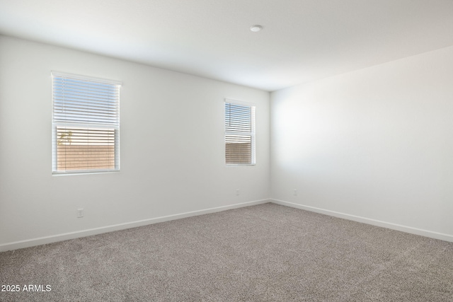 carpeted empty room featuring a wealth of natural light and baseboards