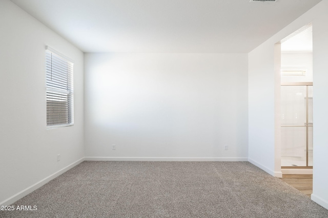 carpeted spare room with visible vents and baseboards