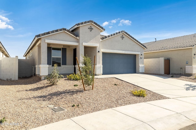 view of front facade with a garage, concrete driveway, a tile roof, fence, and stucco siding