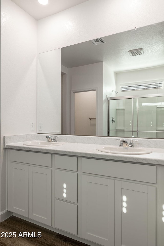 full bath featuring wood finished floors, a stall shower, a sink, and visible vents