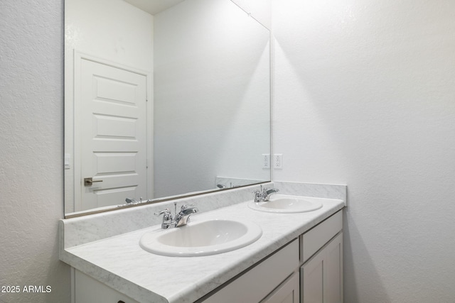 bathroom with a textured wall, double vanity, and a sink