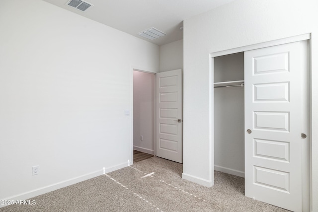 unfurnished bedroom with carpet, a closet, visible vents, and baseboards