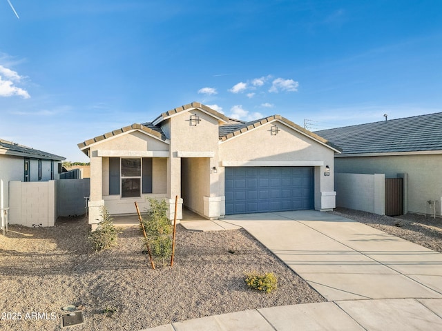 view of front facade featuring a tile roof, stucco siding, concrete driveway, fence, and a garage