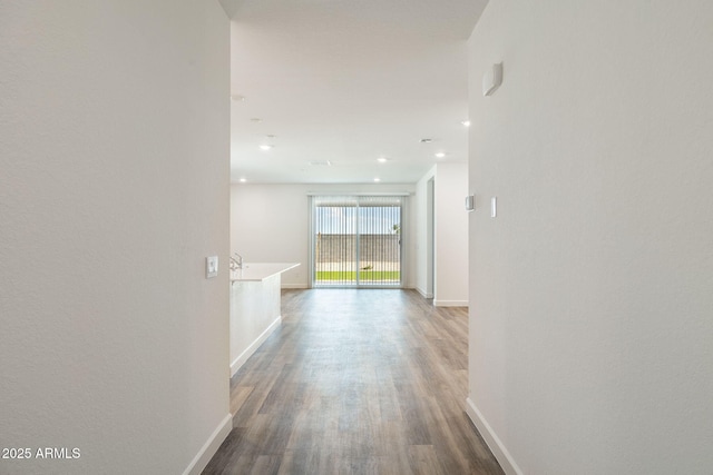 hall featuring recessed lighting, baseboards, and wood finished floors