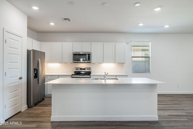 kitchen featuring dark wood-type flooring, appliances with stainless steel finishes, white cabinets, and a sink