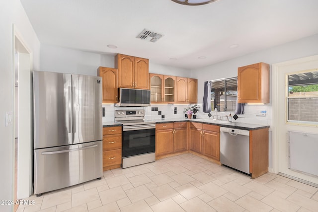 kitchen featuring appliances with stainless steel finishes, light tile patterned floors, sink, and backsplash