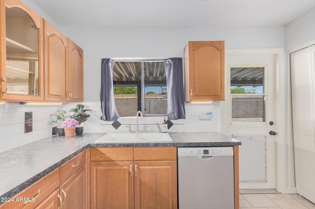 kitchen with glass insert cabinets, dark countertops, dishwasher, and a sink