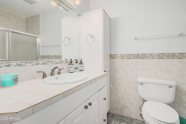 full bath with vanity, a shower stall, toilet, and tile walls