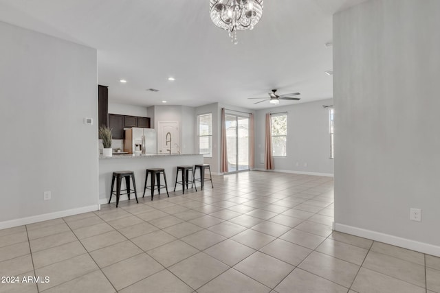 living room featuring ceiling fan with notable chandelier and light tile patterned floors