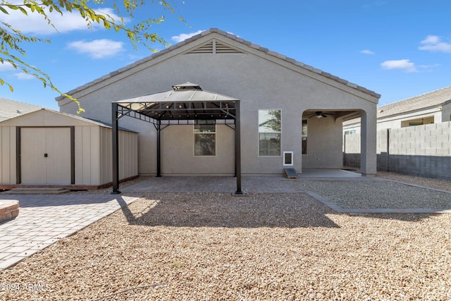 rear view of house with ceiling fan, a storage unit, a gazebo, and a patio area