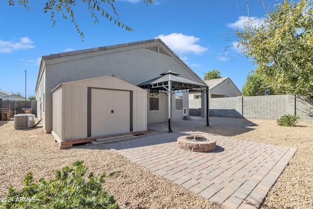 back of property with central AC, a patio, a fire pit, and a storage unit