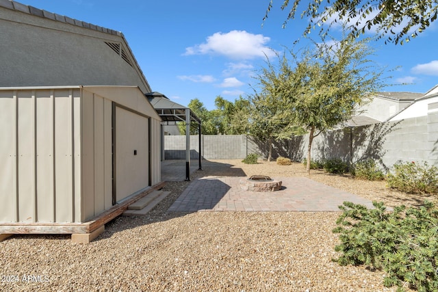 view of yard featuring a patio, a fire pit, and a storage unit