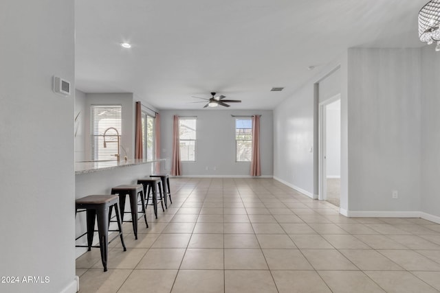 tiled living room with ceiling fan with notable chandelier