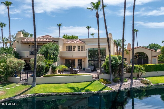 back of house with a balcony, a yard, a water view, and a patio area