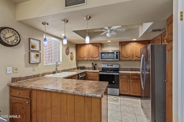 kitchen with stainless steel appliances, a tray ceiling, a sink, and a peninsula