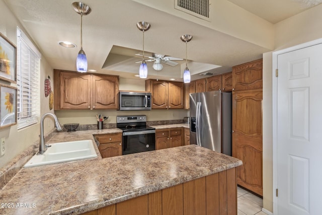 kitchen with visible vents, a peninsula, a tray ceiling, a sink, and stainless steel appliances