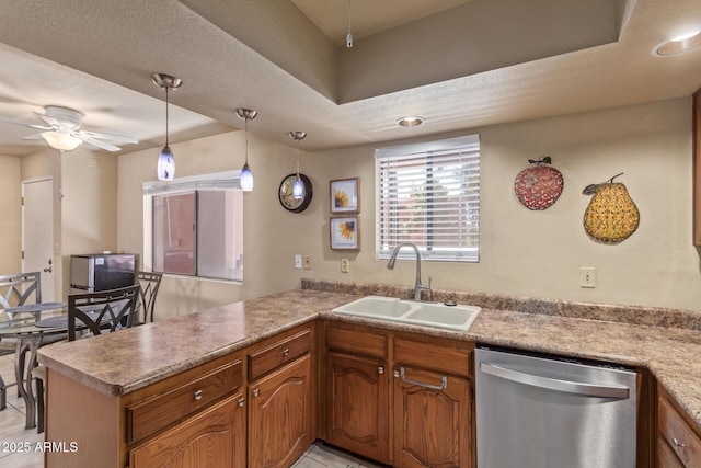 kitchen with stainless steel dishwasher, brown cabinetry, a ceiling fan, a peninsula, and a sink