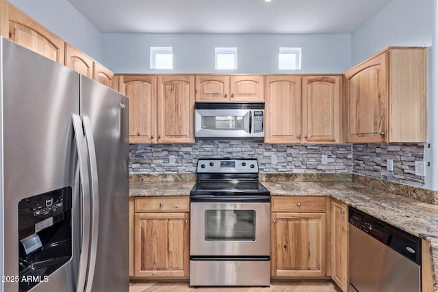 kitchen featuring stainless steel appliances, light stone countertops, light brown cabinets, and decorative backsplash