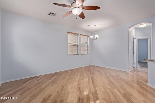 empty room featuring ceiling fan with notable chandelier and light hardwood / wood-style floors