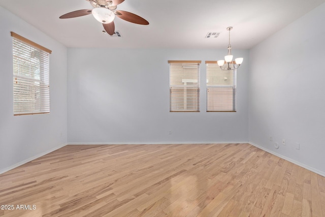 unfurnished room featuring ceiling fan with notable chandelier and light hardwood / wood-style flooring