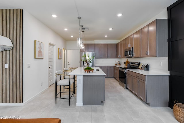 kitchen with light countertops, appliances with stainless steel finishes, a breakfast bar area, and recessed lighting