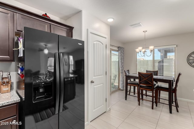 kitchen with dark brown cabinetry, decorative light fixtures, black fridge, and a notable chandelier