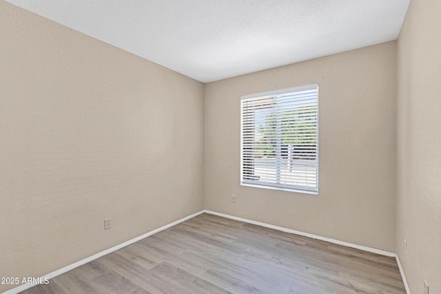 spare room featuring light wood-style floors and baseboards