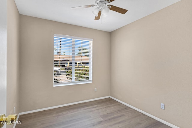 empty room featuring healthy amount of natural light, wood finished floors, and baseboards