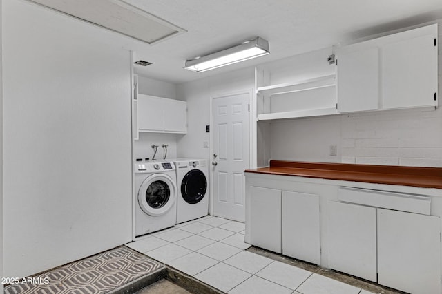 clothes washing area with cabinet space, washing machine and clothes dryer, and light tile patterned floors