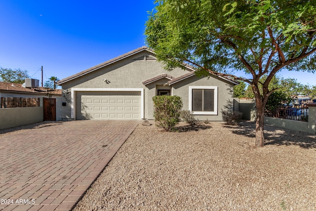 ranch-style home featuring central AC unit and a garage