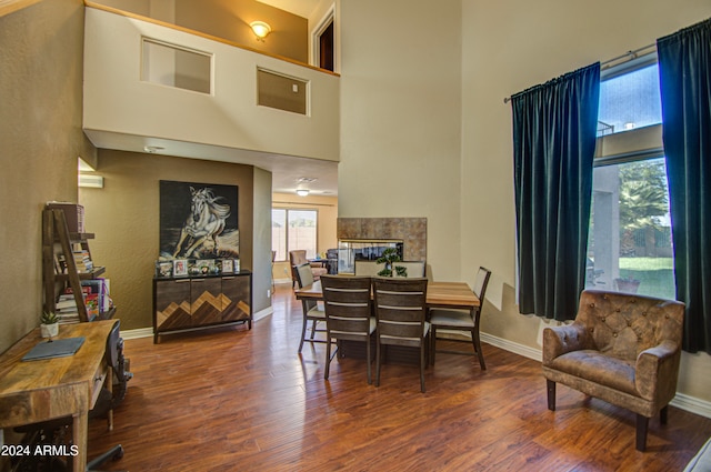 dining area featuring a towering ceiling and hardwood / wood-style flooring