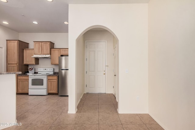 kitchen with light tile patterned floors, stainless steel fridge, and white range with electric stovetop