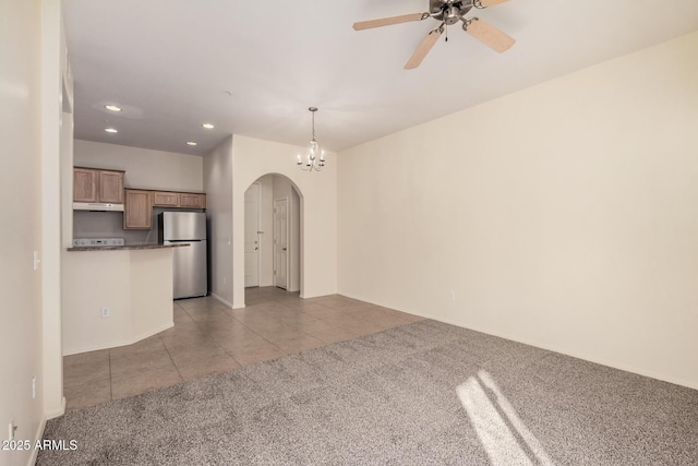 unfurnished living room with light colored carpet and ceiling fan with notable chandelier