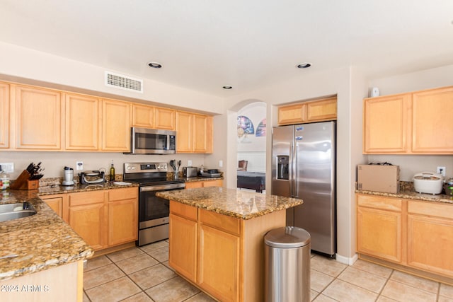 kitchen featuring a kitchen island, stainless steel appliances, light stone counters, and light tile patterned floors