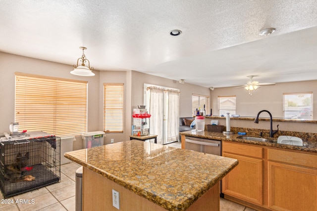 kitchen featuring pendant lighting, light tile patterned floors, a center island, stainless steel dishwasher, and ceiling fan