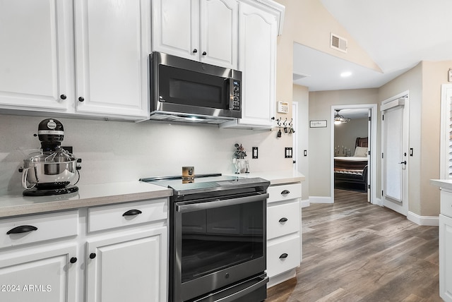 kitchen with hardwood / wood-style flooring, lofted ceiling, white cabinetry, and appliances with stainless steel finishes