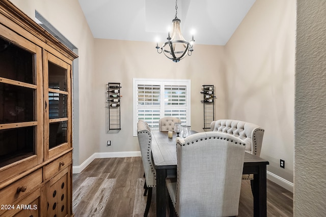 dining space featuring dark wood-type flooring, a chandelier, and vaulted ceiling