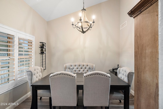 dining room with dark hardwood / wood-style flooring, lofted ceiling, and an inviting chandelier