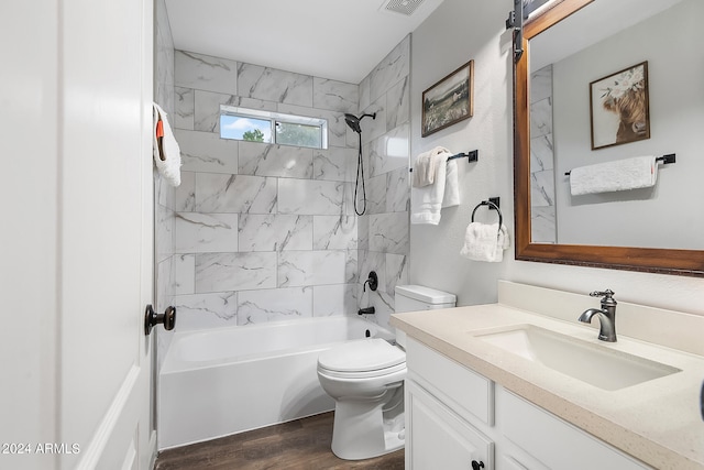 full bathroom with vanity, tiled shower / bath combo, hardwood / wood-style flooring, and toilet