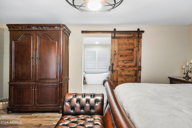 bedroom with a barn door and light hardwood / wood-style flooring