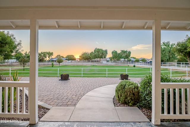 patio terrace at dusk featuring a lawn