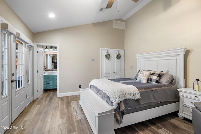 bedroom with ensuite bathroom, ceiling fan, sink, hardwood / wood-style flooring, and lofted ceiling