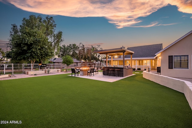 yard at dusk featuring a patio area and exterior bar