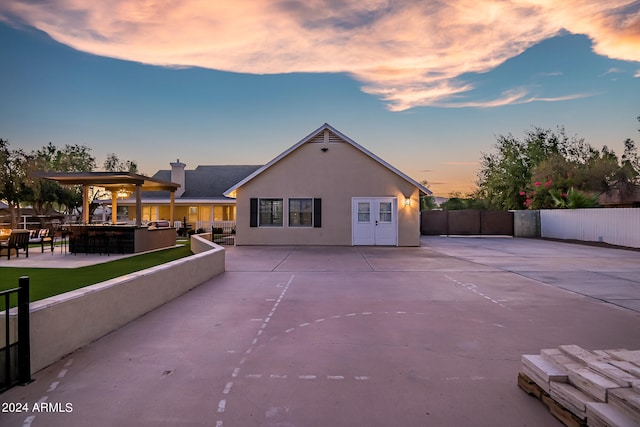 back house at dusk featuring a bar and a patio